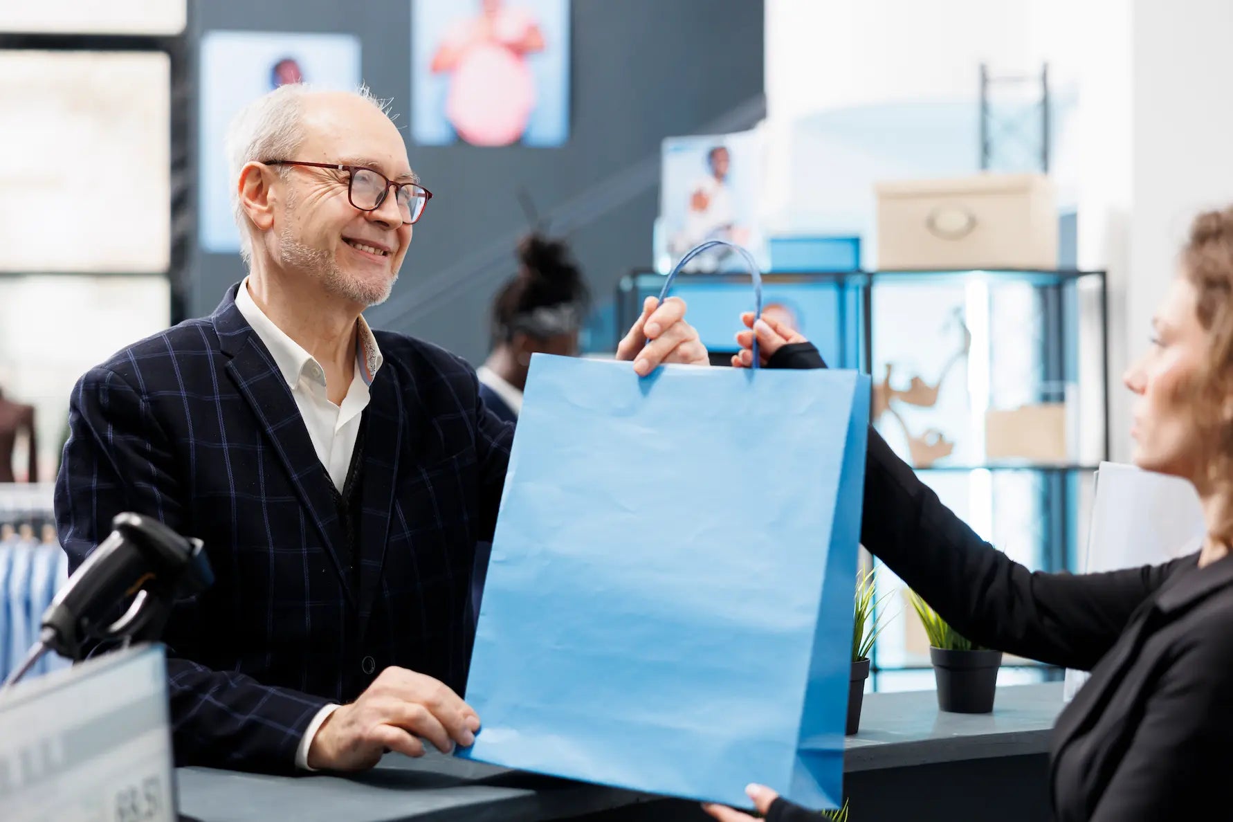 Person receiving a blue shopping bag from a store employee.