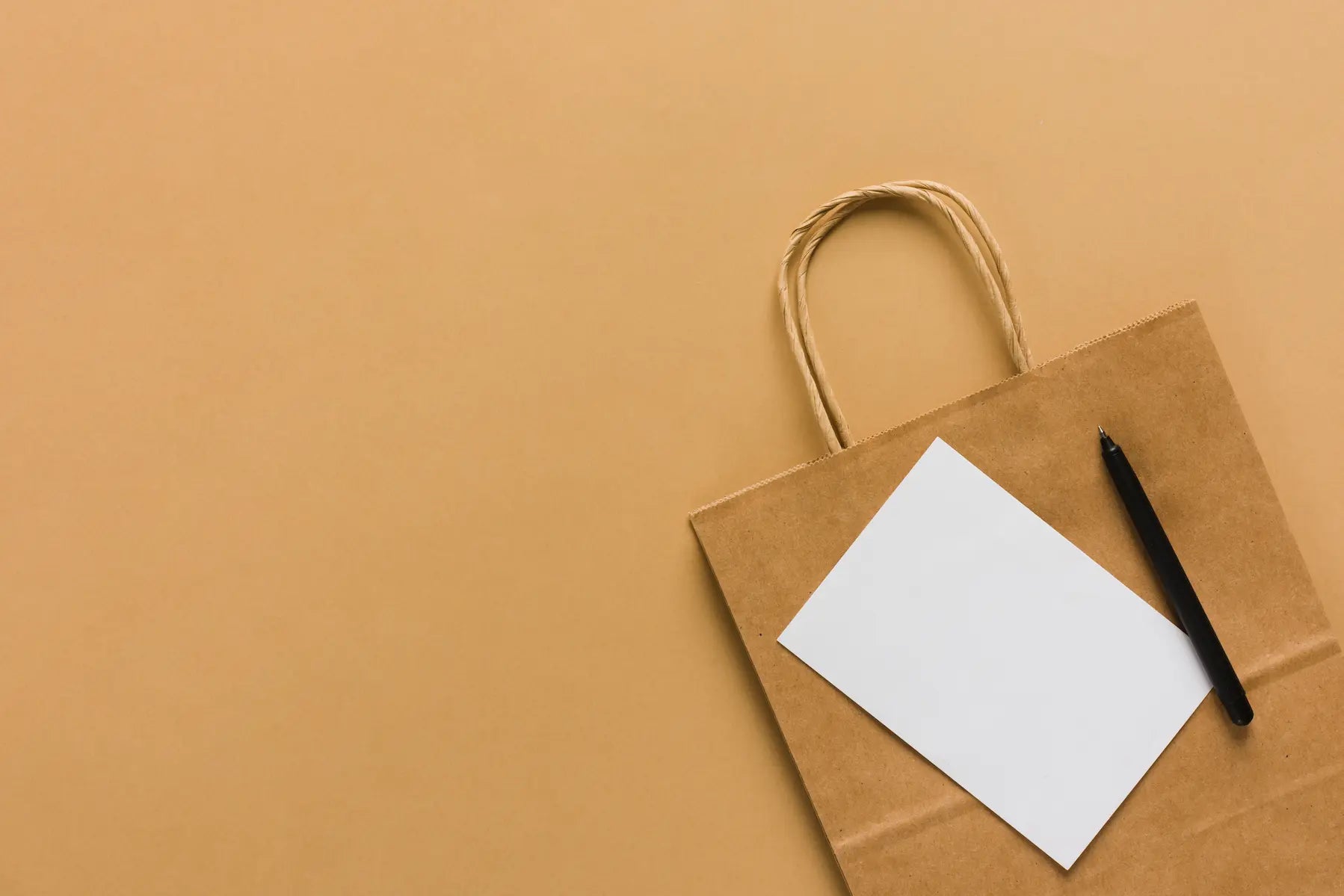 Brown paper bag with a white sheet of paper and black pen on a brown background
